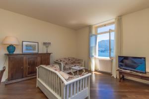 a room with a crib and a television and a chair at Apartment Anna - Griante in Griante Cadenabbia