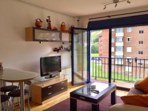 a living room with a table and a television and a balcony at La Barquera in Ribadesella