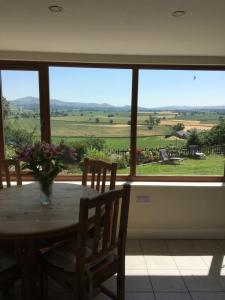 a dining room table with a view of the countryside through a window at The View in Welshpool