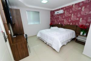 1 dormitorio con cama blanca y pared roja en Hotel Paraiso en Correia Pinto