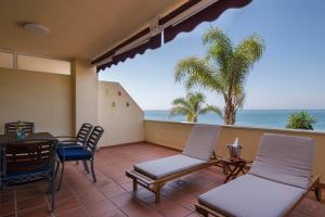 patio z krzesłami i stołem oraz oceanem w obiekcie Relax Frente al Mar w mieście Benalmádena