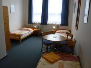 プラハにあるホテル ハサのベッド2台、テーブル、椅子が備わる客室です。