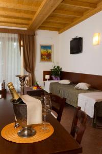 una habitación con 2 camas y una mesa con una botella de champán en Locanda Ristorante al Cardellino, en Bardolino