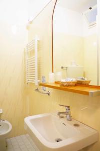 La salle de bains est pourvue d'un lavabo, d'un miroir et de toilettes. dans l'établissement Hotel Vergilius, à Riccione