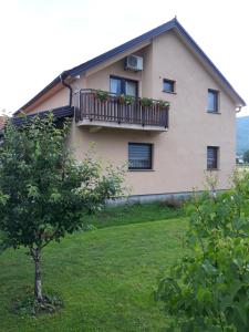 a house with a balcony and a tree at Guest House Vana in Korenica