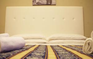 a bed with a white headboard and a rug at Hotel Vergilius in Riccione