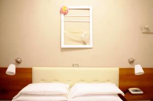 Hotel Vergilius في ريتشيوني: سرير مع وسادتين بيضاء ومرآة