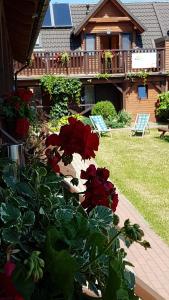 a house with a deck with red flowers on it at Pensjonat na Zaciszu in Kąty Rybackie