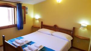 a bedroom with a bed with towels on it at La Baia Apartments in Putzu Idu