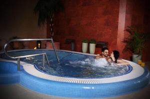 un hombre y una mujer en un jacuzzi en un hotel en Xavin Wellness Hotel & Restaurant en Harkány