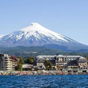 une montagne enneigée devant une ville avec une montagne dans l'établissement Departamento en Pucon, à Pucón