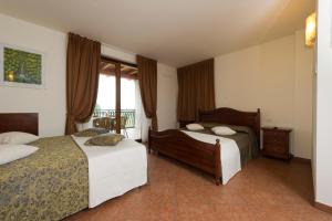 a hotel room with two beds and a window at Locanda Ristorante al Cardellino in Bardolino