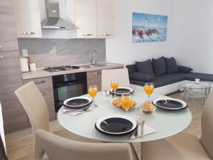 a white dining room table with chairs and glasses of orange juice at Apartment Stipe in Maslenica