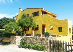 a yellow house with a fence in front of it at La Baia Apartments in Putzu Idu
