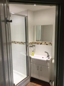 a white bathroom with a sink and a shower at The George Inn in Wells