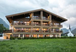 a large building with a balcony and a church at Wagner's Aparthotel in Pertisau