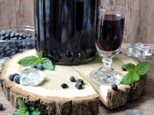 a glass of wine and blueberries on a wooden table at Malinovy Sen in Habovka