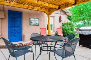 a patio with a table and chairs and a blue door at Casa La Huerta in Albuquerque