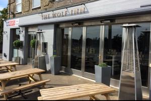 a restaurant with wooden benches in front of a building at The Wolf Inn in Lowestoft