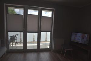 ein Wohnzimmer mit einem großen Fenster mit Blick auf eine Terrasse in der Unterkunft Apartament Berlin in Świnoujście + 30 Fotos