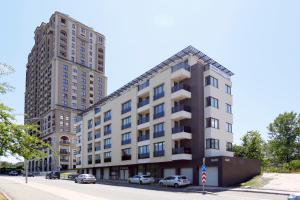 two tall buildings on a city street with cars parked at Lovely Sunrise - първа линия морска градина in Burgas City