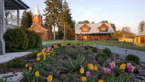 un jardín con flores frente a una iglesia en Villa Spełnione Marzenia en Okuninka