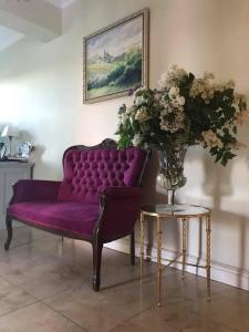 a purple couch and a table with a vase of flowers at Villa Spełnione Marzenia in Okuninka