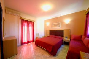 a bedroom with a red bed and a couch at Hotel Palazzo in Archangelos
