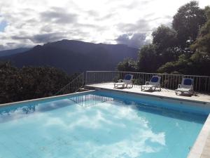 una piscina con sillas y montañas en el fondo en Hotel Esmeralda, en Coroico