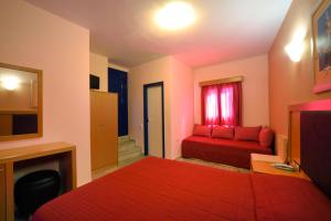 um quarto de hotel com uma cama vermelha e um sofá em Hotel Palazzo em Archangelos