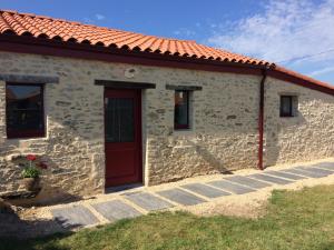 une maison en pierre avec une porte rouge et un toit rouge dans l'établissement La grange, à Machecoul