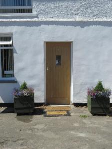 a door in a white building with two potted plants at Anchor House in Alford