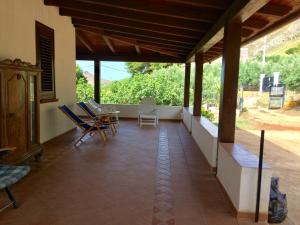 a porch of a house with chairs and a table at Villa con piscina in Castellammare del Golfo