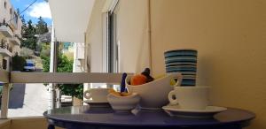 einen Tisch mit Tassen und eine Schale Obst darauf in der Unterkunft Spacious Apartment in the Historical Center of Athens in Athen