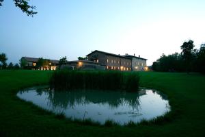 a pond in a field with a building in the background at Relais Corte Guastalla Apartments in Sona