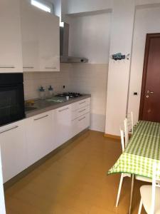 eine Küche mit weißen Schränken und einem Tisch mit grüner Tischdecke in der Unterkunft Vient e mare (Sea wind) in Torre Annunziata