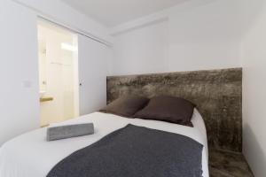 セトゥーバルにあるFran Pacheco 39 (downtown apartment)の白いベッド1台(木製ヘッドボード付)が備わるベッドルーム1室が備わります。