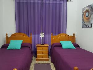 two beds in a bedroom with purple curtains at Atico con Vistas al Mar, Garachico in Garachico
