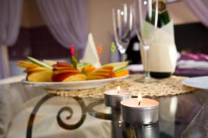 two candles on a glass table with a plate of fruit at Hotel Abazhur-ZURO in Ulyanovsk