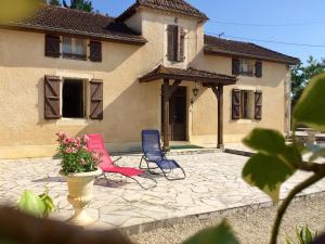 two chairs sitting on a patio in front of a house at La Cordillière in Laveraët
