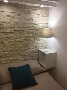 - une chambre dotée d'un mur en pierre avec un lit et une lampe dans l'établissement Le Casette Gargallo 2 - Ortigia, à Syracuse
