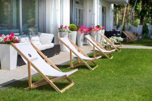 a row of lawn chairs sitting in the grass at Majestique in Pobierowo