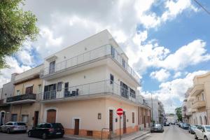 a white building with a balcony on a street at Casa Angela Rosa in Carovigno