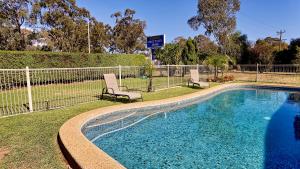 a swimming pool with two chairs next to a fence at Euroa Motor Inn in Euroa