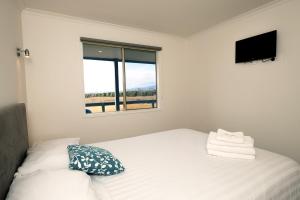 a white bedroom with a bed and a window at Prom Gate Getaway in Yanakie
