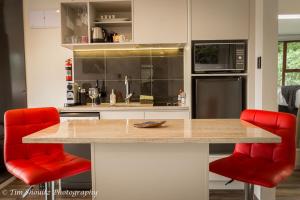a kitchen with red chairs and a counter top at Whare Manu Boutique Cottage in Invercargill