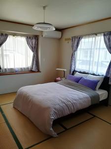 a bedroom with a large bed and two windows at Jukichi Owada Residence in Sendai