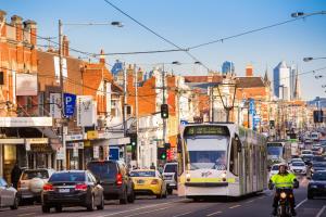 a bus driving down a busy city street with traffic at Parkville Place Serviced Apartments in Melbourne +22 photos