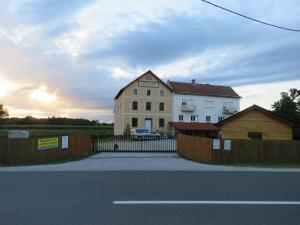 una gran casa blanca con una valla delante en Mill House Apartment and Camping, en Ljutomer