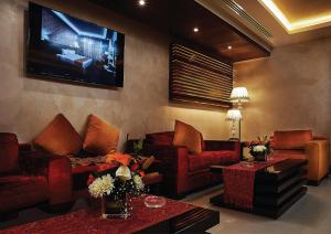 a living room with red couches and a flat screen tv at Seven Roses Hotel in Amman